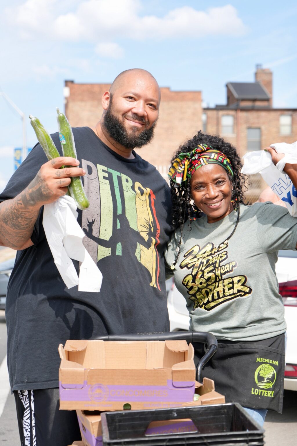 Volunteers smiling with fresh cucumbers at Food Donation Day