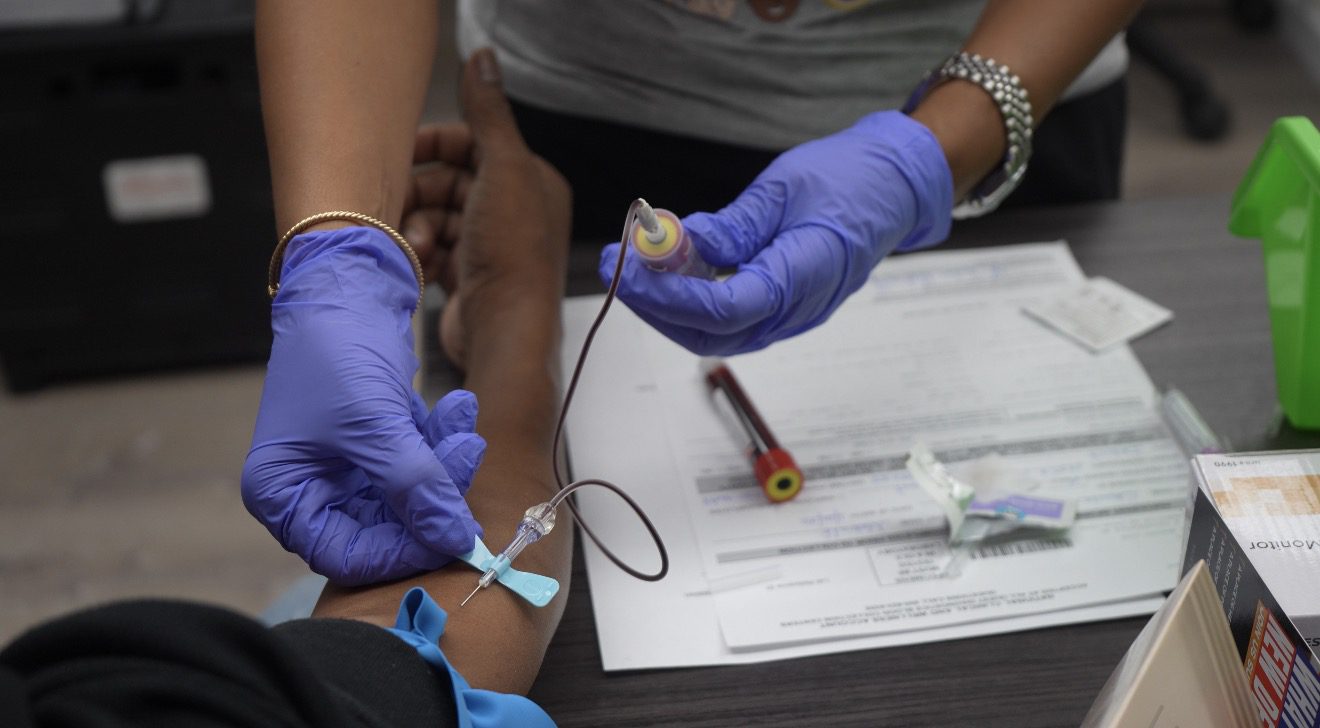 A health worker draws blood for a prostate cancer screening test at DABO Detroit