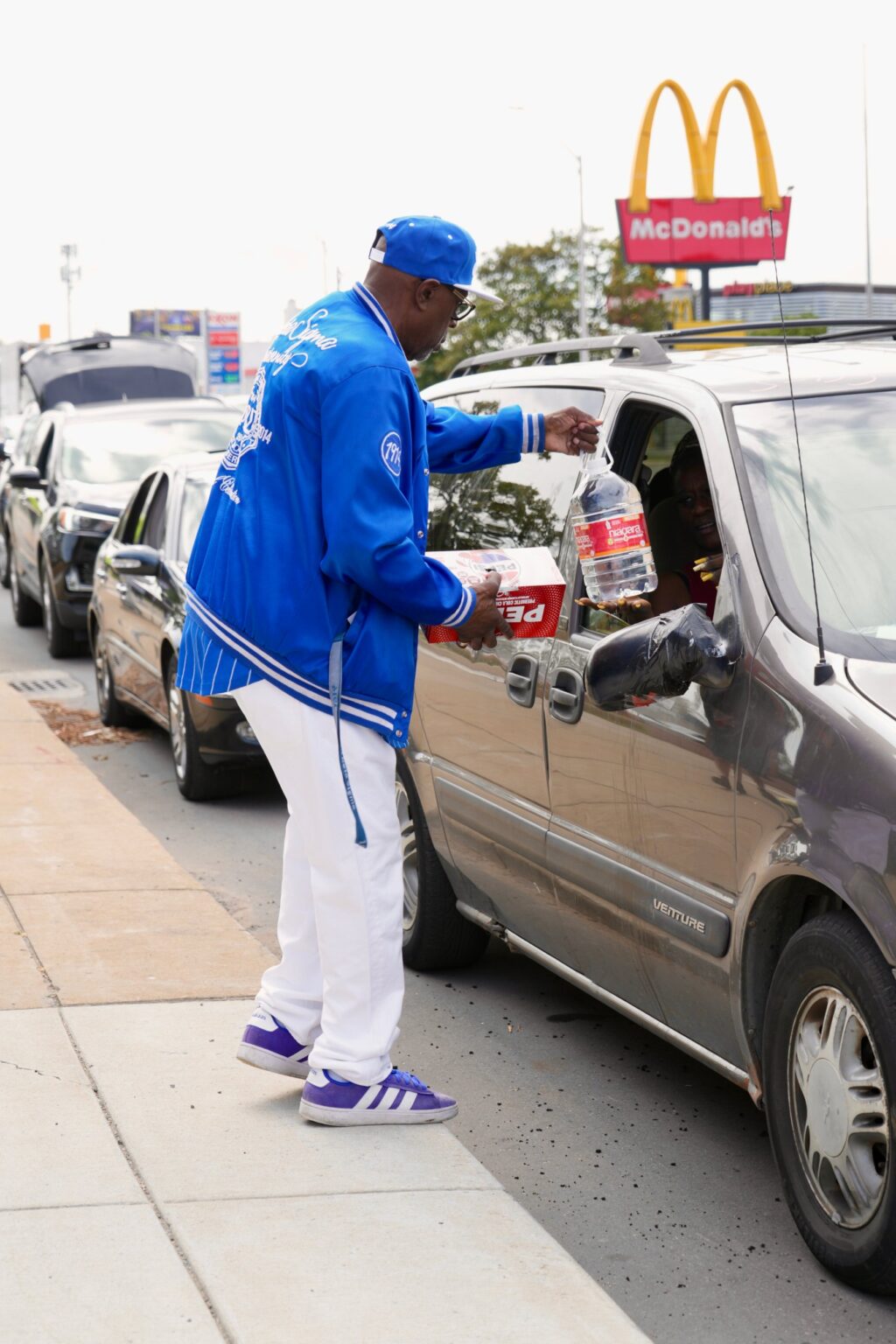 A volunteer handing water to a driver